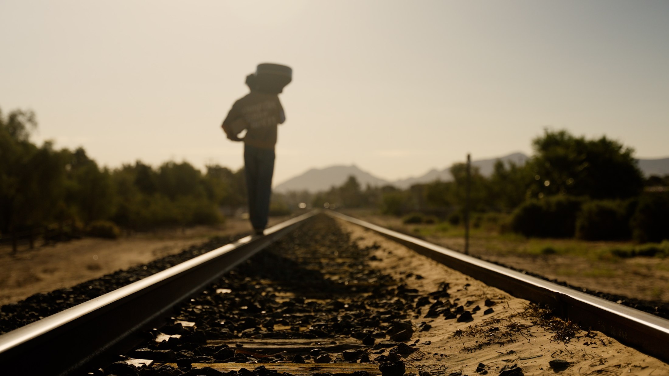 Artist walking along desert rail lines